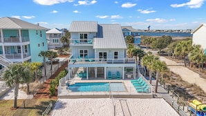 A large, multi-story house with a swimming pool, a covered deck, and a view of the ocean.