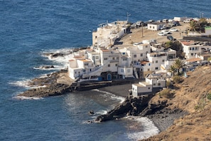 A coastal village with white buildings, rocky shoreline, and a clear view of the sea.