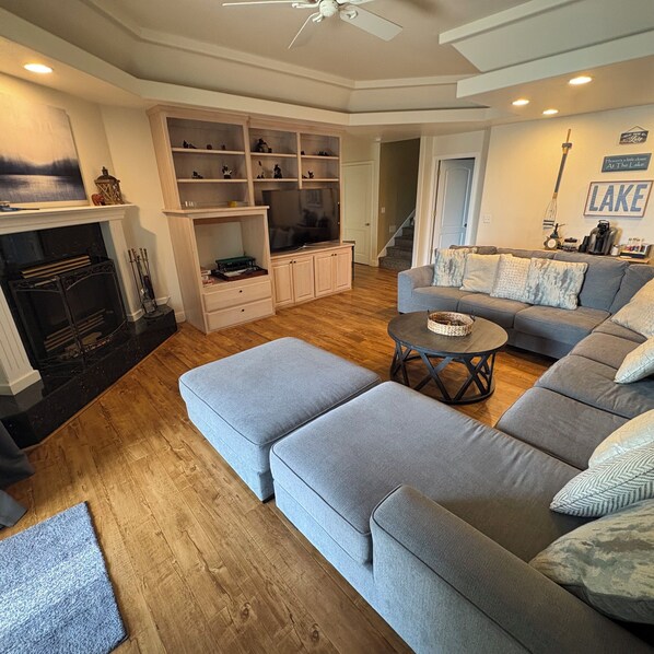 A living room with a fireplace, a sectional sofa, a coffee table, and built-in shelving.