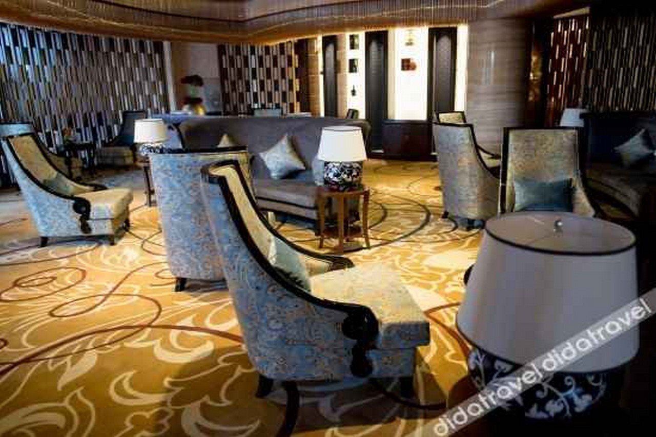 A lobby with patterned carpet, seating with lamps, and a modern design.