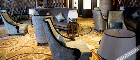 A lobby with patterned carpet, seating with lamps, and a modern design.