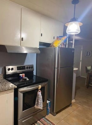Enjoy cooking in this well-equipped kitchen with a refrigerator, oven, and granite countertop.