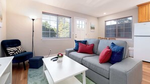 A living room with a grey sofa, a white coffee table, a blue armchair, and a floor lamp. - Bright, Quiet, Comfy 1BR Cottage in Mountain View (Mountain View)