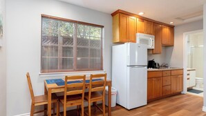 A kitchen with wooden cabinets, a white refrigerator, and a window with blinds. - Bright, Quiet, Comfy 1BR Cottage in Mountain View (Mountain View)
