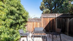 A patio with a wooden fence, a metal bench, and a chair. - Bright, Quiet, Comfy 1BR Cottage in Mountain View (Mountain View)