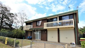 A two-story building with a balcony, a garage, and a fenced yard. - Bear's a well located fisherman and family holiday home in Harrington (Harrington)