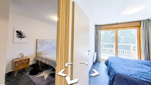 Ett sovrum med en säng, ett nattduksbord, en sänggavel, ett fönster med gardiner och utsikt över en terrass.