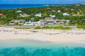 A coastal property with multiple houses, a swimming pool, and a beach.