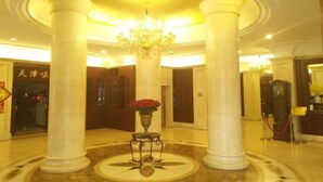 Un lobby espacioso con techos altos, grandes columnas y un candelabro central.