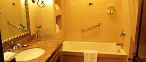 A bathroom with a sink, mirror, and bathtub.
