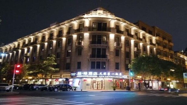 Un hotel de varios pisos con un diseño arquitectónico clásico, que presenta una entrada destacada y una fachada bien iluminada.