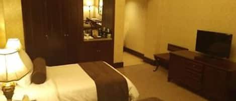 A hotel room with two beds, a dresser, a television, and a mirror.