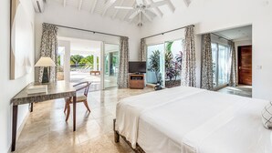 Une chambre spacieuse avec un grand lit, un bureau avec une chaise, une télévision et un balcon avec des rideaux.
