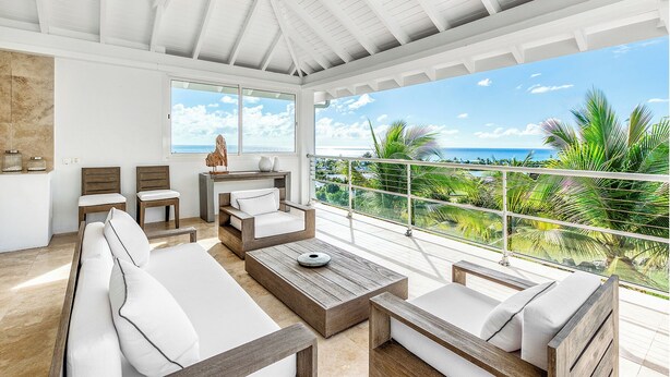 Un balcon spacieux offrant une vue sur l’océan et les palmiers.