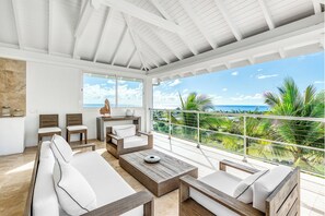 Un balcon spacieux offrant une vue sur l’océan et les palmiers.
