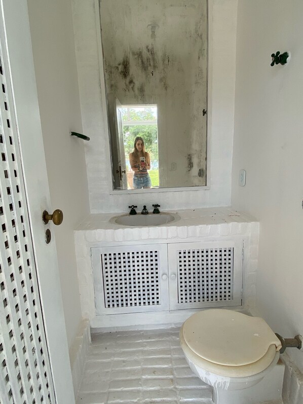 Un baño con un lavabo blanco, un espejo encima y un inodoro.