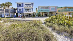 A beachfront property with multiple-story houses, a sandy beach, and some vegetation.