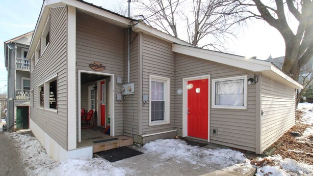 Un bâtiment d’un seul étage avec une porte rouge et une porte de garage.