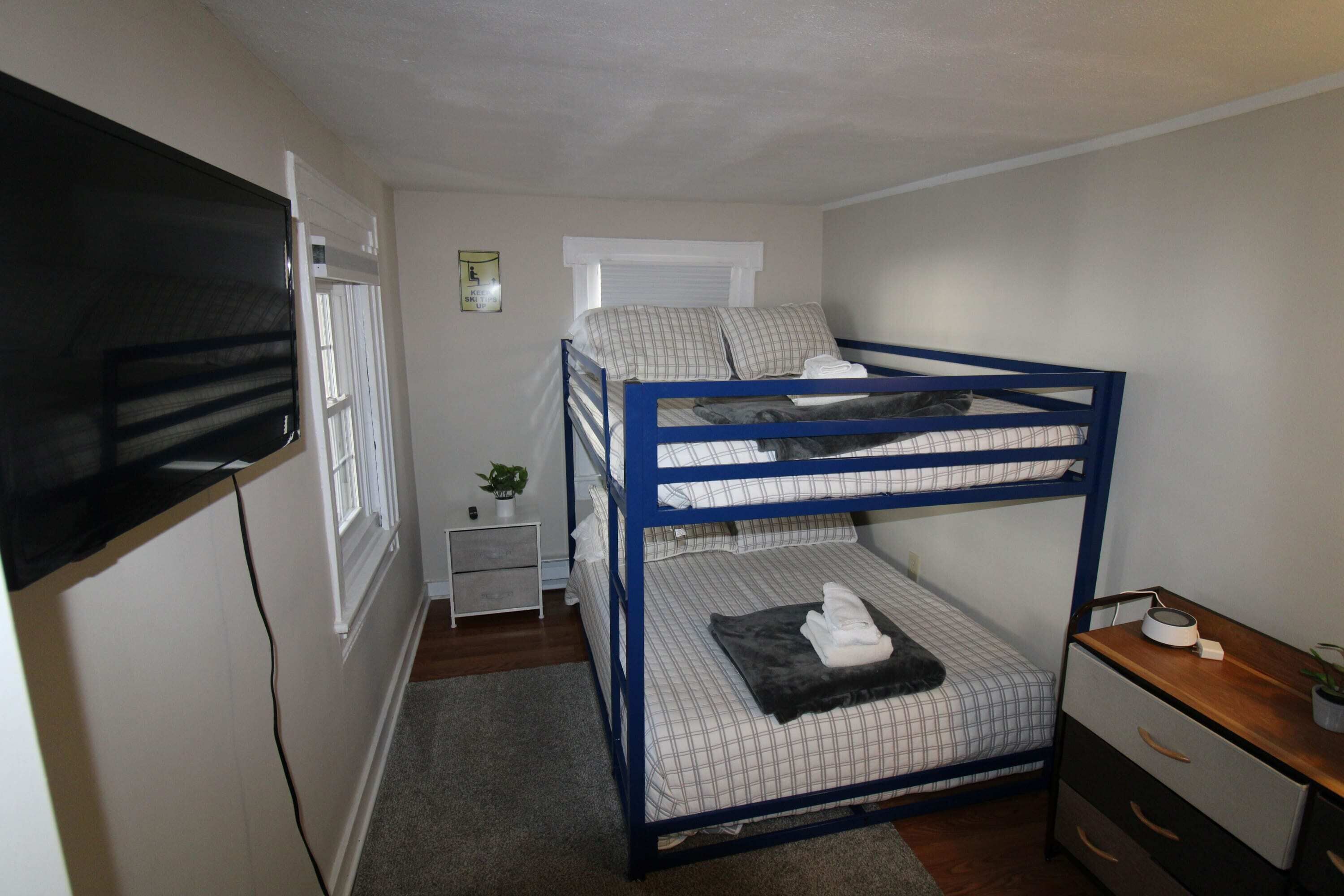 A bunk bed room with a TV, bedside table, and a small window.