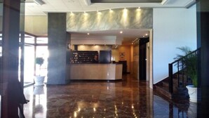 Eine Lobby mit einer Rezeption, Marmorböden und einer Treppe.
