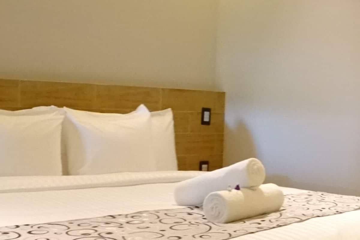 Une chambre d’hôtel avec un grand lit, une tête de lit dotée d’un éclairage intégré et une table de chevet avec un téléphone.