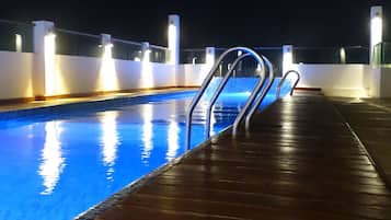 Una piscina al aire libre, sillones reclinables de piscina