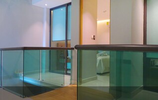 Una habitación de hotel moderna con un separador de vidrio, una cama y una pequeña zona de estar.
