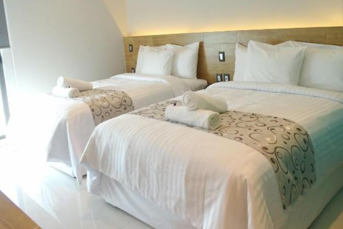A modern hotel room with two beds, white linens, and a minimalist design.