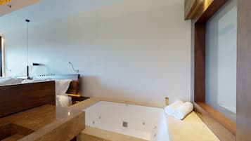 Un baño moderno con una bañera grande, un tocador de madera y un aplique de pared.