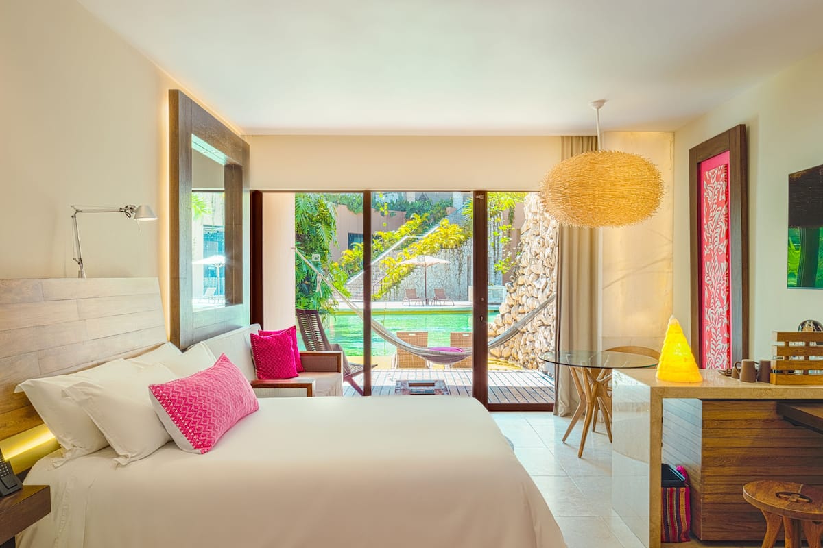 Habitación de hotel moderna con una cama grande, un escritorio con silla, un área de comedor y televisión.
