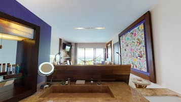Une salle de bain dotée d’un grand miroir, d’une baignoire, d’un lavabo et d’une fenêtre donnant sur l’océan.
