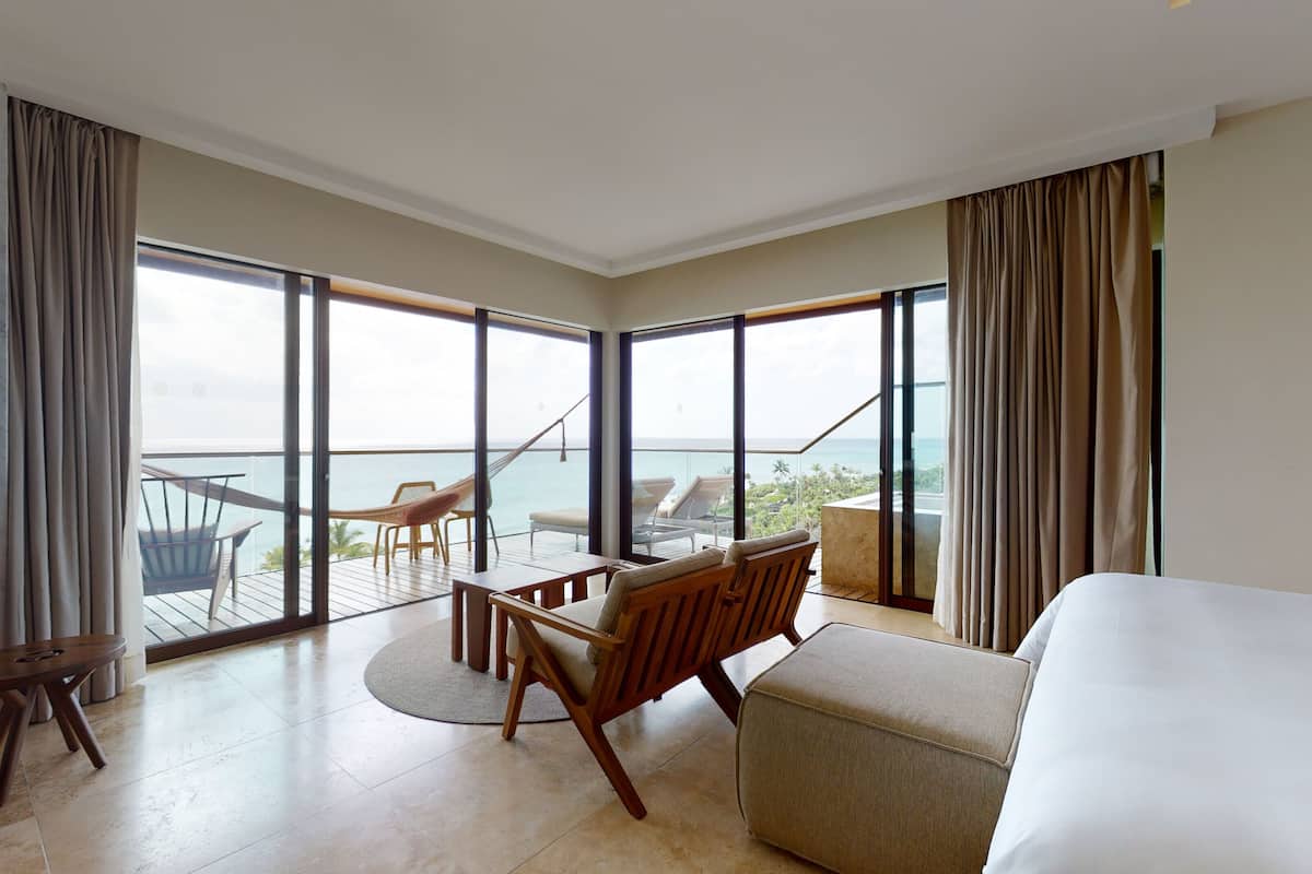 Habitación de hotel con un balcón grande, una cama, un escritorio y una silla.