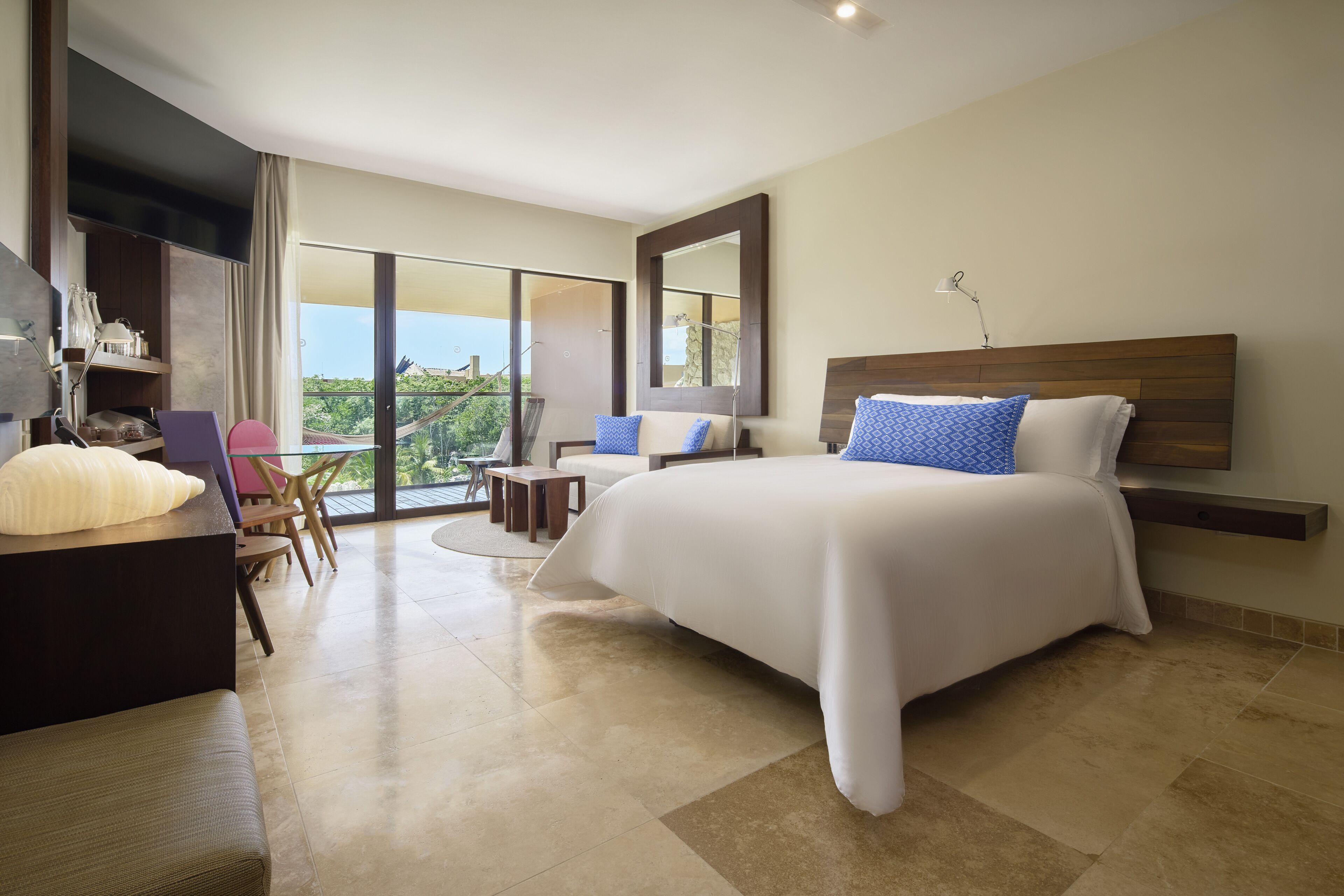 Een moderne hotelkamer met een groot bed, een bureau, een stoel en een balkon met uitzicht.