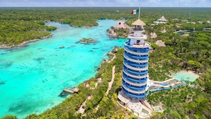 A resort with a central tower, clear turquoise waters, and lush greenery. - Hotel Xcaret Arte - All Parks / All Fun Inclusive, Adults Only - All inclusive (Playa del Carmen)