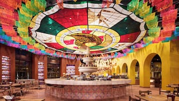 Un restaurant doté d’une fontaine centrale, avec des tables et des chaises disposées autour.