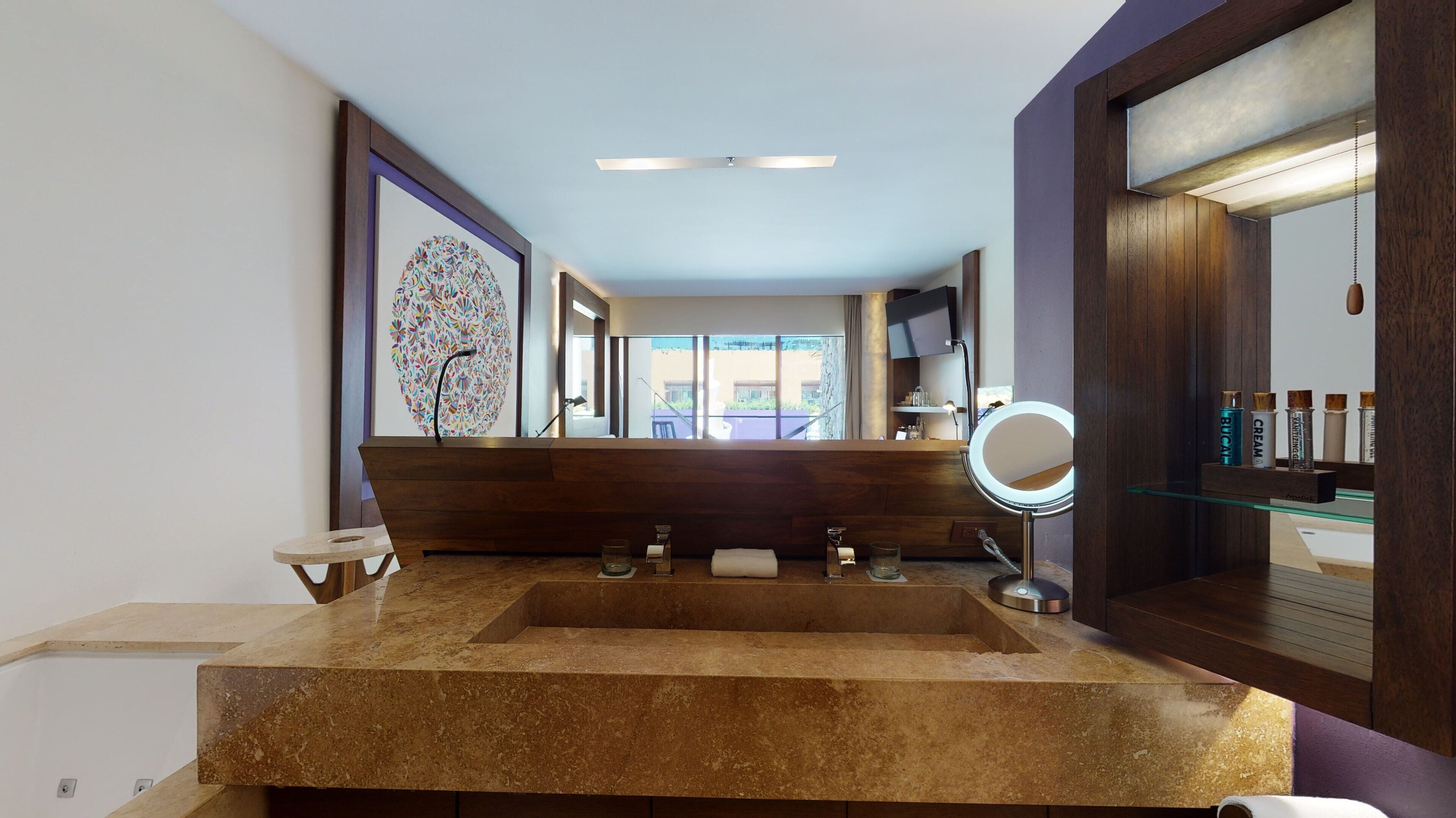 A bathroom with a large sink, a mirror, and a view of the outside.