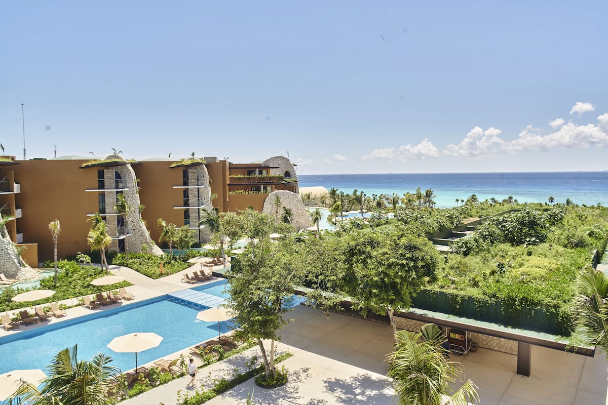 Un resort con piscina, palmeras y vista al océano.