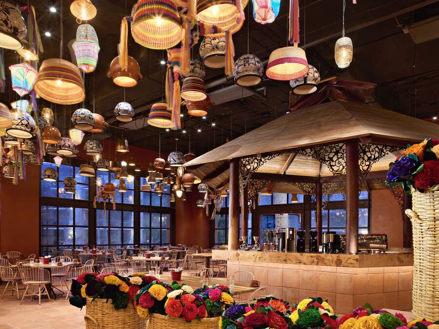 A restaurant with hanging lanterns, wicker baskets with flowers, and a bar area.