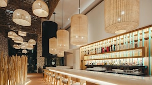 A bar area with wooden chairs, a long counter, and hanging wicker lamps. - Hotel Xcaret Arte - All Parks / All Fun Inclusive, Adults Only - All inclusive (Playa del Carmen)