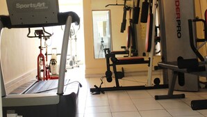 A gym with a treadmill, weight machines, and a mirror. - Residence Les Hauts de L Indenie (Abidjan)