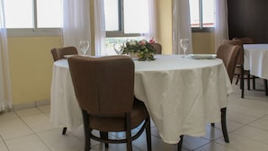 A dining area with a round table, chairs, and a vase of flowers. - Residence Les Hauts de L Indenie (Abidjan)