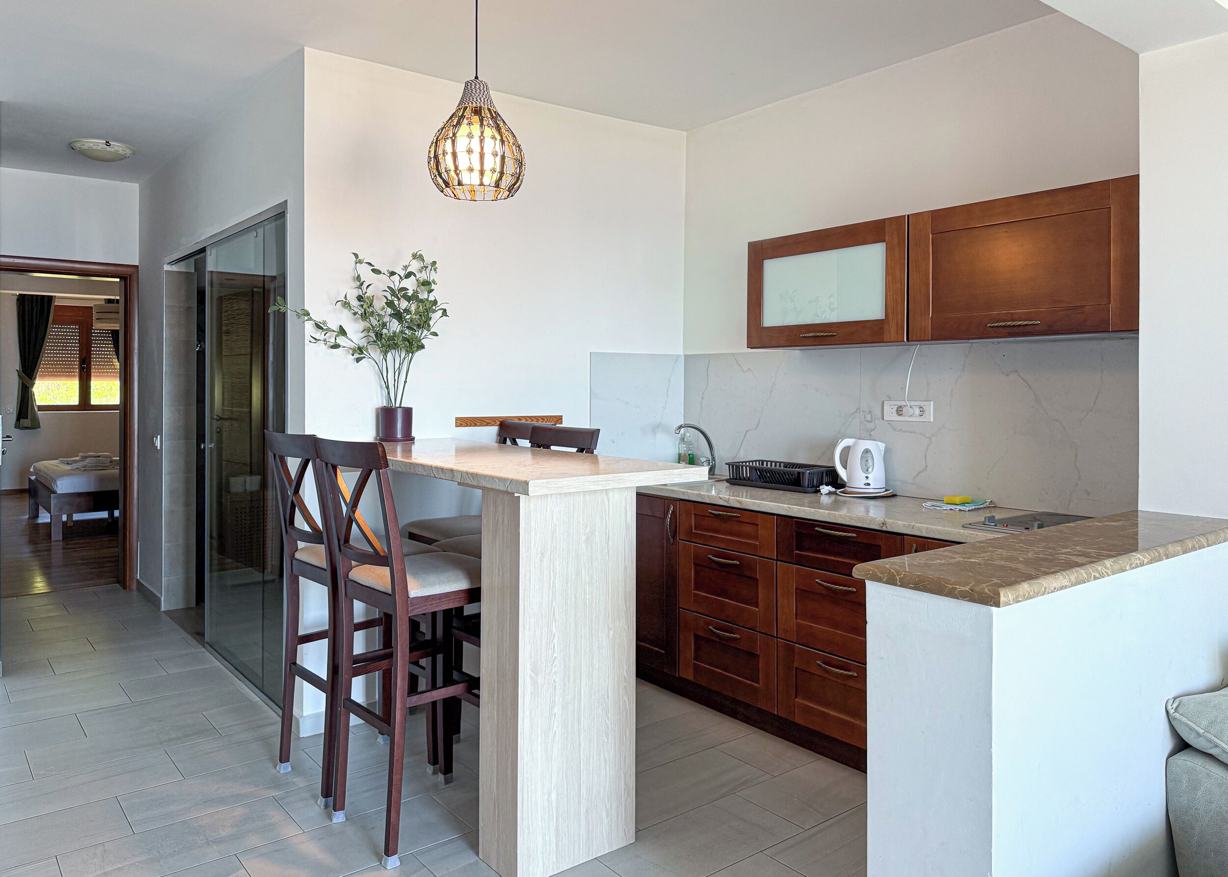 Een moderne keuken met een centraal eiland, houten kasten en een hangende lamp.