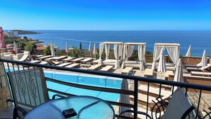 A poolside area with sun loungers and umbrellas, overlooking a clear blue sea. - Arabela 2 Apartments (Utjeha)
