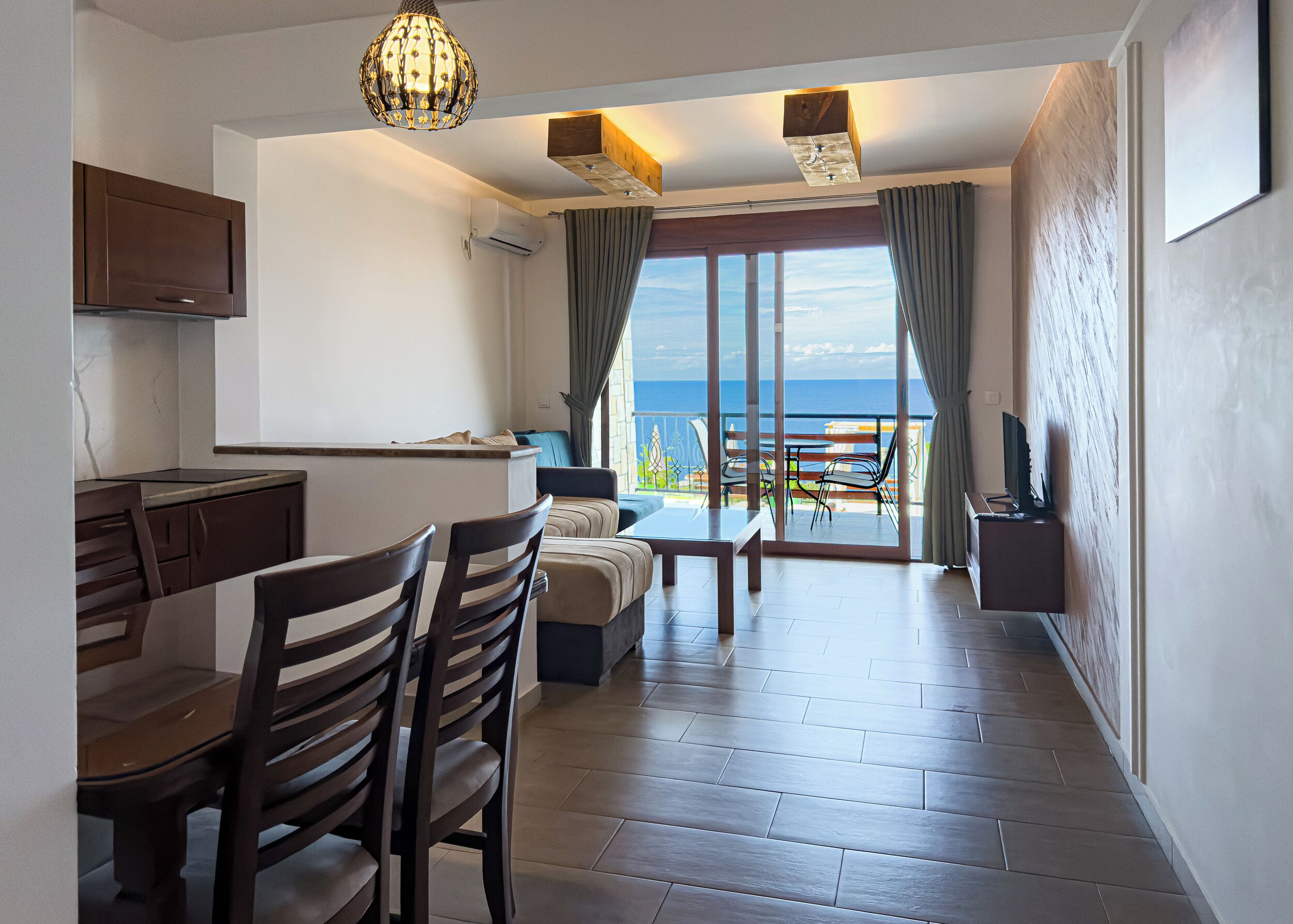 Een moderne woonkamer met een eetgedeelte, een keuken en een balkon met uitzicht op zee.