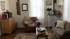Ein Wohnzimmer mit einem braunen Sofa, einem gemusterten Teppich, einer Holzkabine und einem kleinen Tisch mit Büchern.