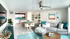 A modern living room with a grey sofa, a wooden coffee table, and a dining area with a round table and chairs. - Ocean View, Spacious Condo next to Pool (St Thomas)