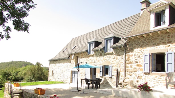 A stone building with a patio, outdoor seating, and flower planters. - Country home (Montboudif)