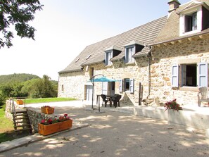 A stone building with a patio, outdoor seating, and flower planters. - Country home (Montboudif)
