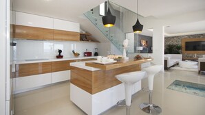 Une cuisine moderne avec un îlot central en bois, des meubles blancs et deux suspensions lumineuses.