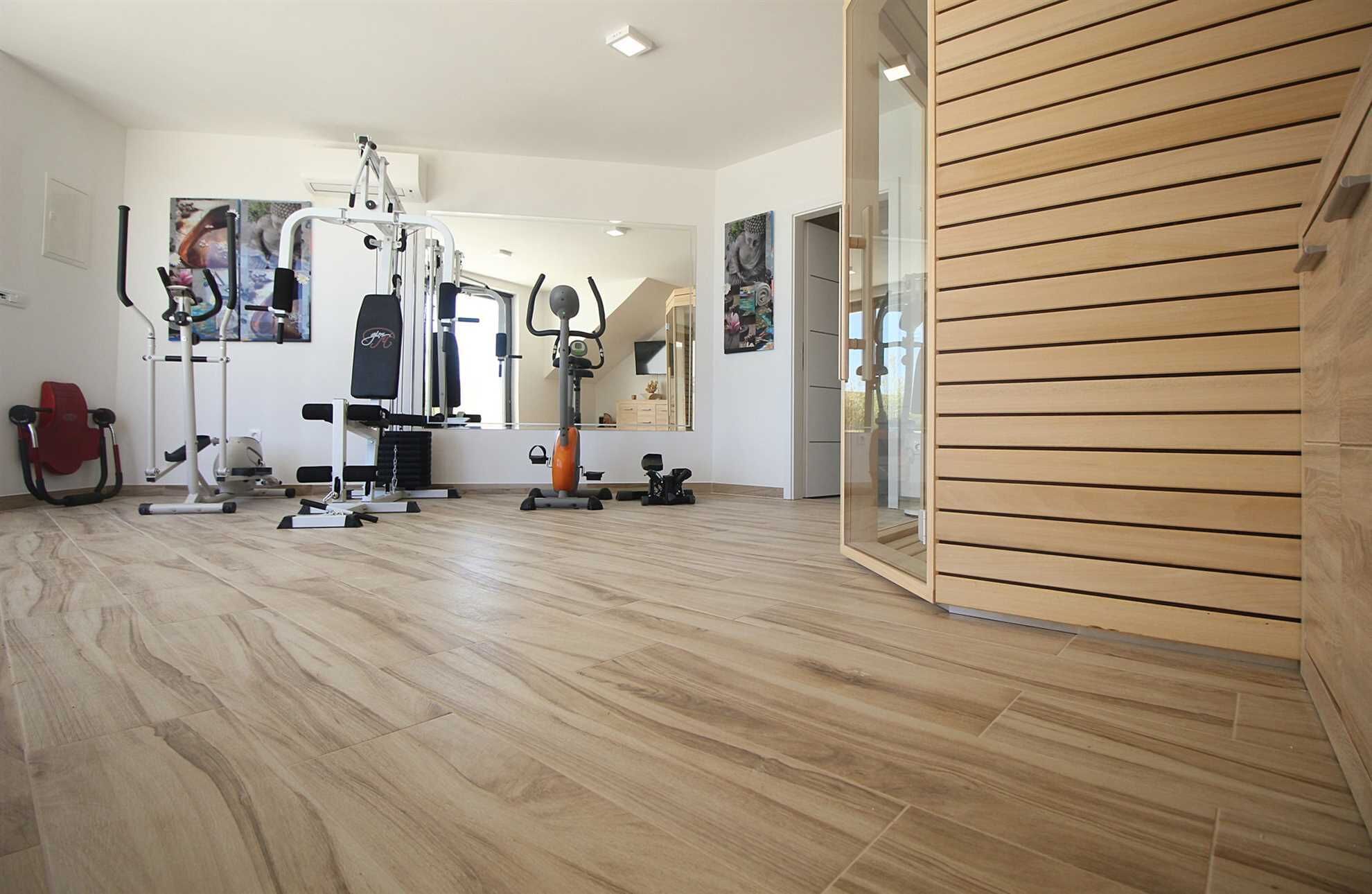 A gym with various exercise equipment, a mirror, and a wooden wall.